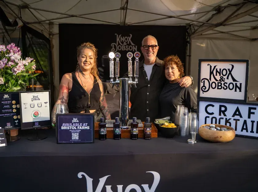 Craft beverage booth with three vendors, beer taps, bottled drinks, and Knox Johnson sign at a market stall.