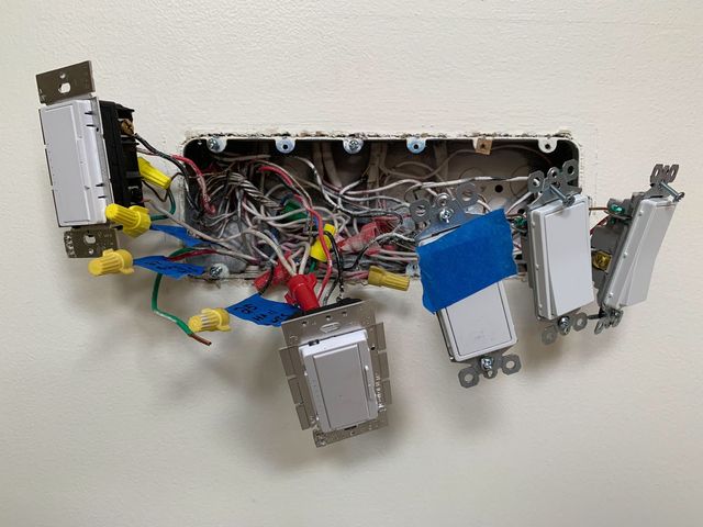 A bunch of wires are laying on a white wall.