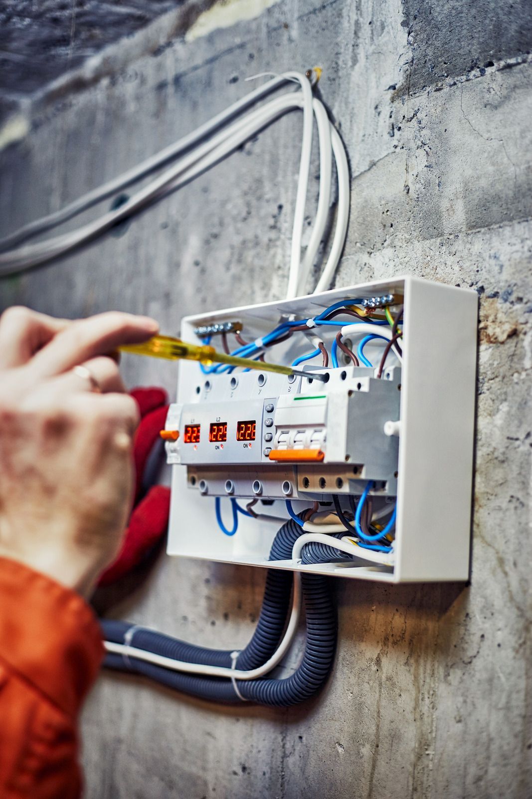 A person is working on an electrical box with a screwdriver.