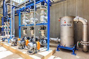 A stainless steel tank with pumps and pipes in a factory.