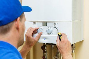 A man is fixing a boiler with a screwdriver.