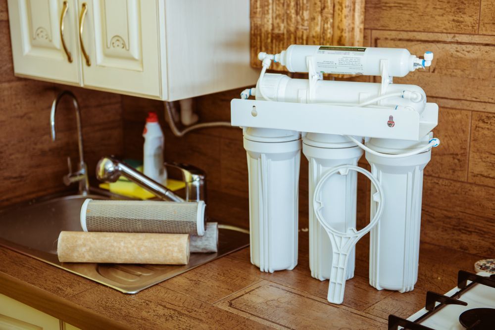 A Water Filter is Sitting on a Kitchen Counter Next to a Sink — MacKenzie Plumbing In West Mackay, QLD