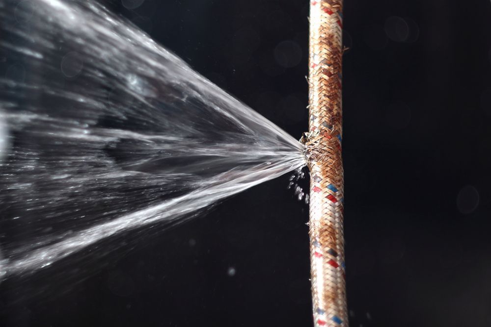 A Close Up of a Water Pipe With Water Spraying Out of It — MacKenzie Plumbing in West Mackay, QLD