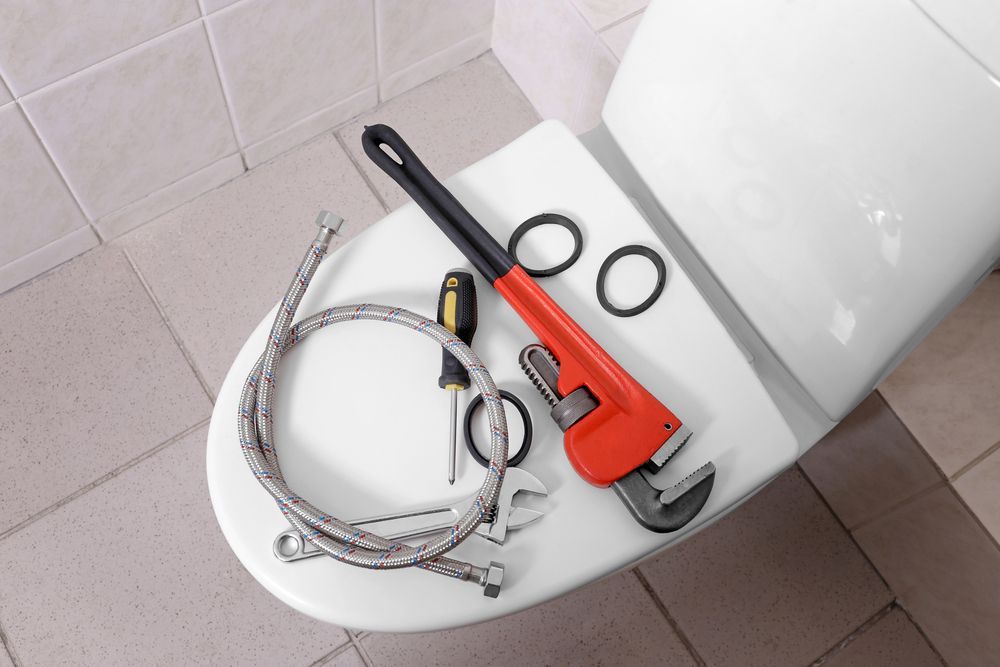A Toilet With a Wrench and Hose on It — MacKenzie Plumbing In Ooralea, QLD