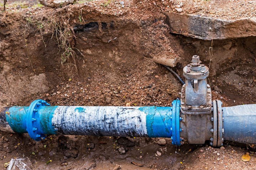 A Blue Pipe With a Valve is Sitting in the Dirt — MacKenzie Plumbing In West Mackay, QLD