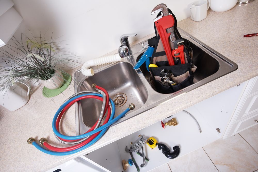 A Kitchen Sink With a Lot of Tools in It — MacKenzie Plumbing In West Mackay, QLD