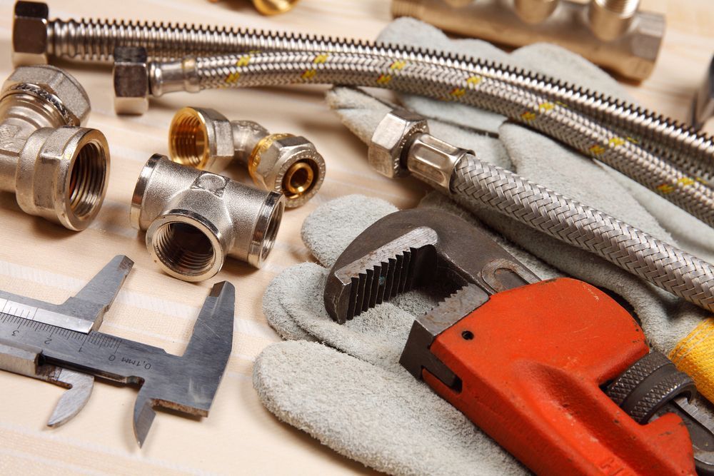 A Plumber's Tools and Hose Are on a Wooden Table — MacKenzie Plumbing In Marian, QLD