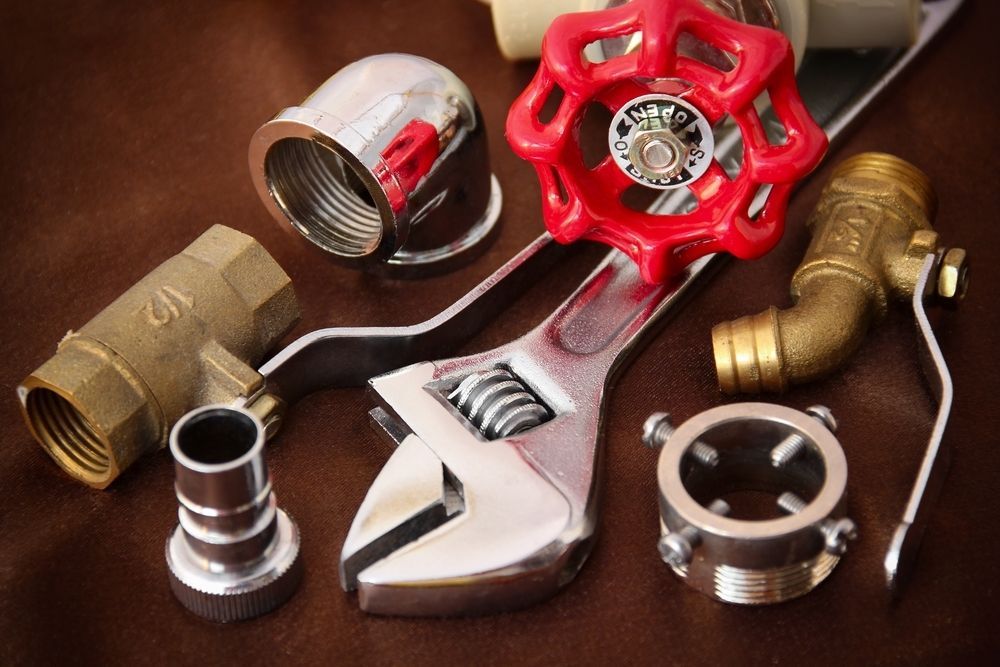 A Wrench With a Red Handle is Surrounded by Plumbing Parts — MacKenzie Plumbing In Walkerston, QLD