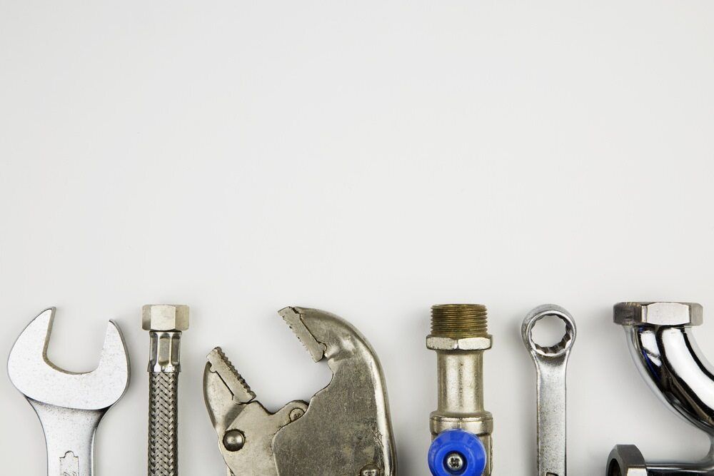 A Bunch of Plumbing Tools Are Lined Up on a White Surface — MacKenzie Plumbing In Ooralea, QLD