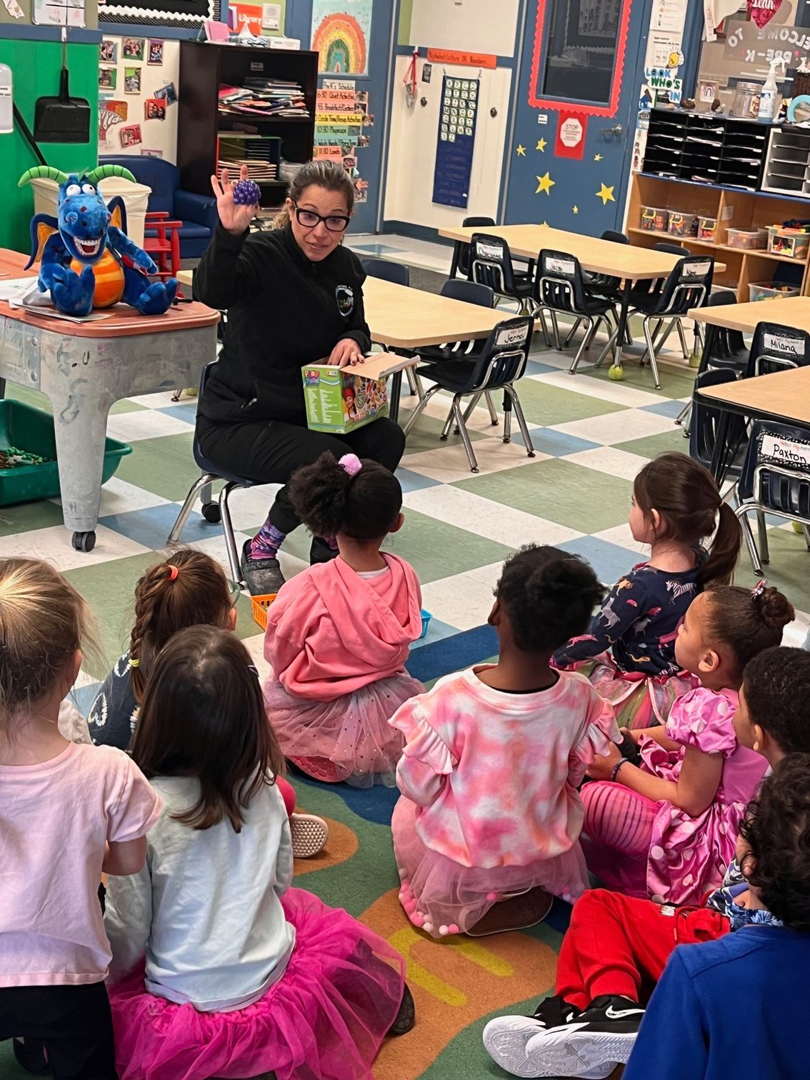 A woman is reading a book to a group of children in a classroom.