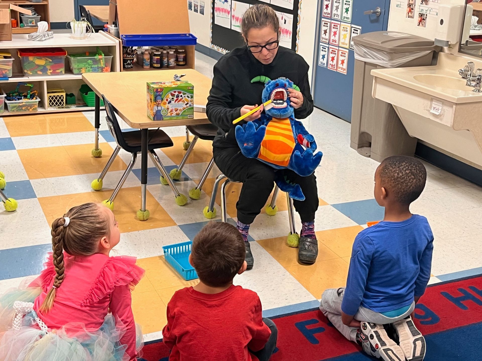 A woman is reading a book to a group of children in a classroom.