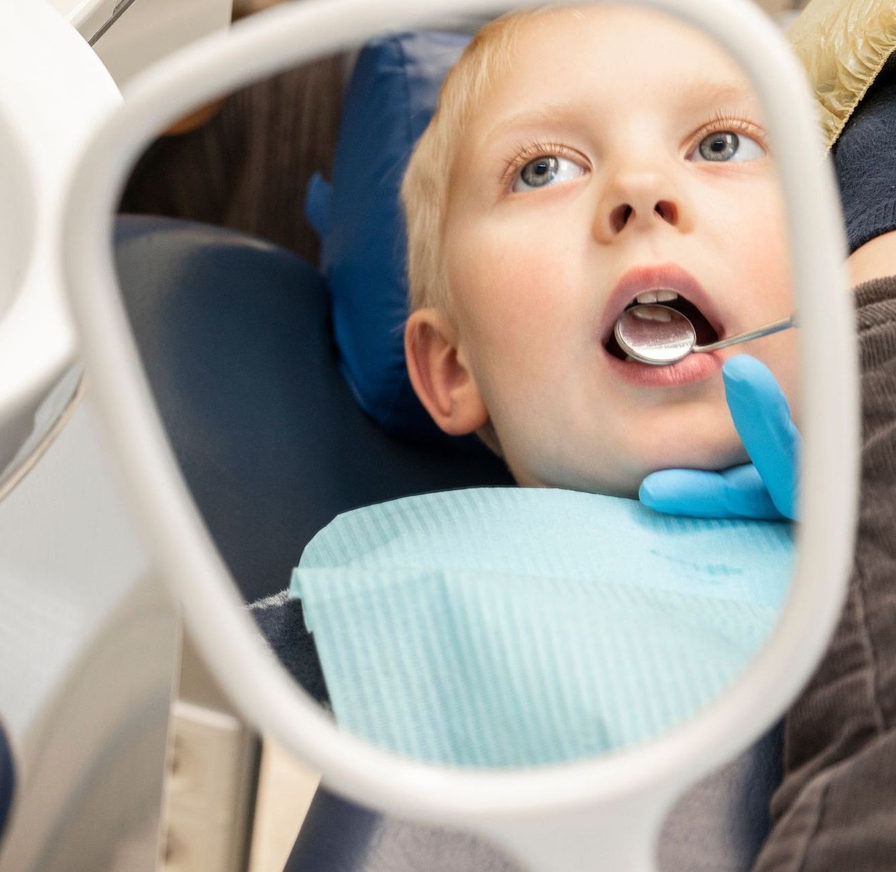 A young boy is getting his teeth examined by a dentist