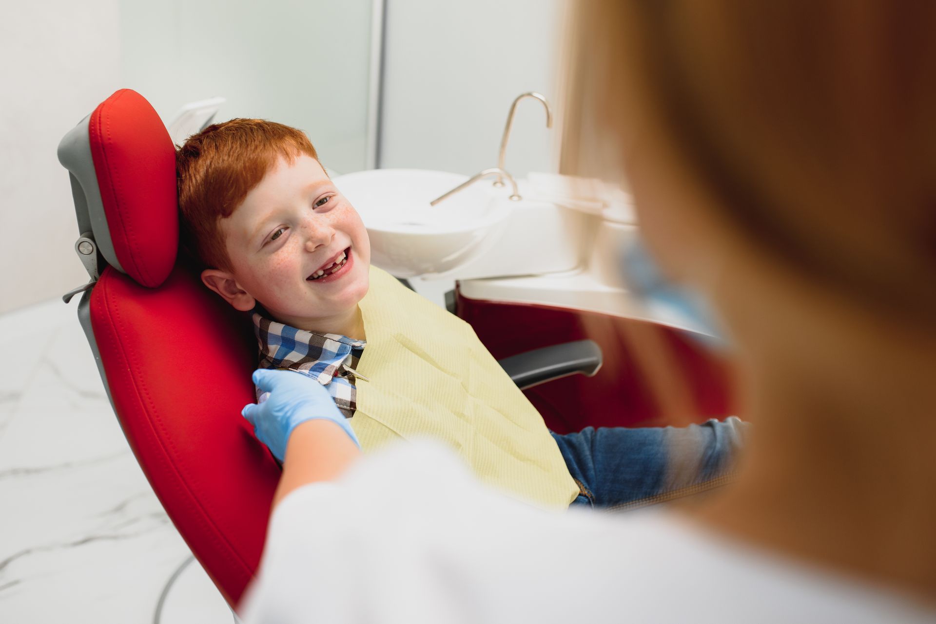 Compassionate pediatric dentist at Swede Square, East Norriton, PA. A young boy is sitting in a dental chair and smiling at the dentist.