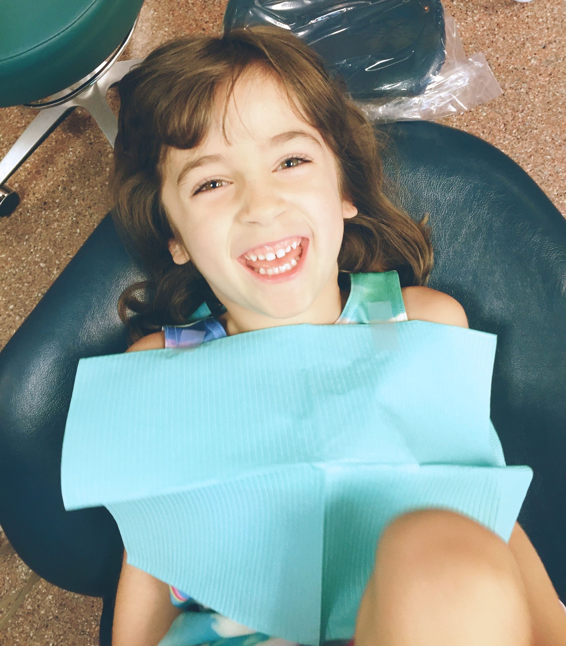 Child laying back in dentist chair smiling.