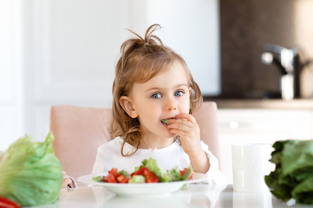 Child eating strawberries at a table in a bright kitchen
