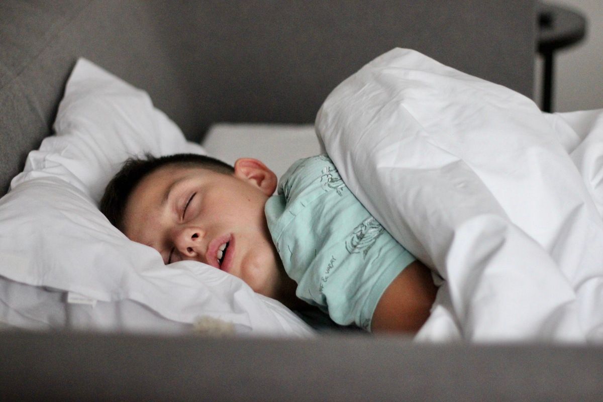 Sleeping child in a bed with white pillows and blanket