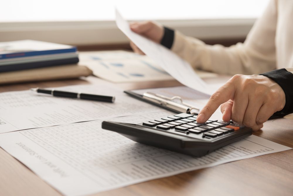 Person Using a Calculator, Surrounded by Paperwork, Accounting — Accountsloop Tax & Business Advisory in Geelong, VIC