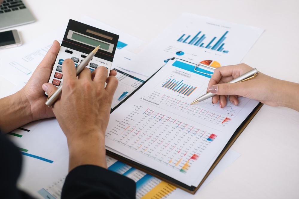 Two People Reviewing Financial Reports With a Calculator, Pens, and Charts on a White Table — Accountsloop Tax & Business Advisory in Geelong, VIC