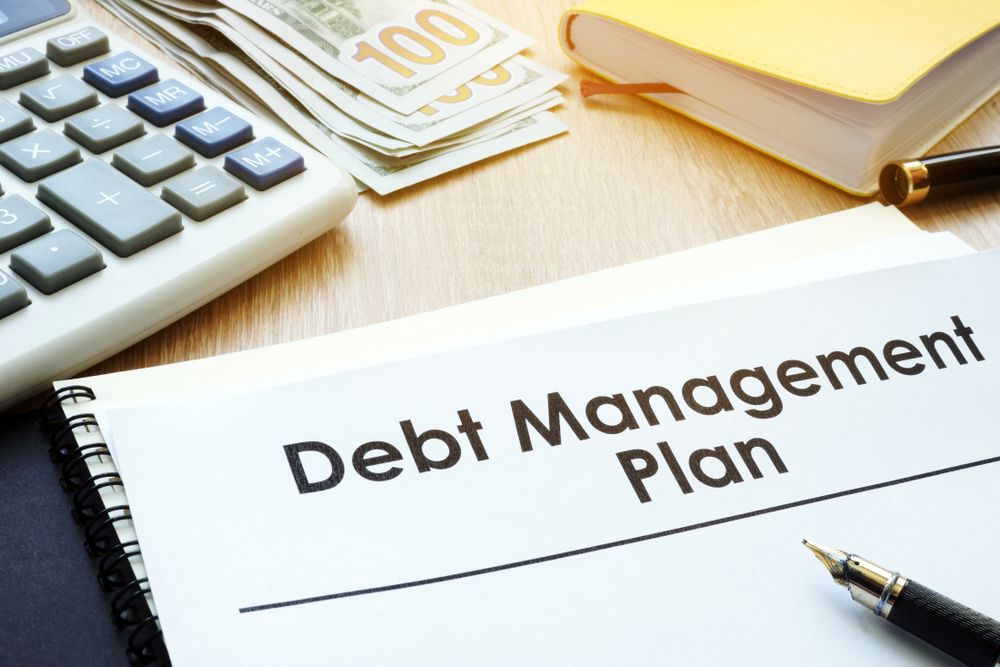 Debt Management Plan Notebook, Calculator, Cash, Pen on a Wooden Desk — Accountsloop Tax & Business Advisory in Geelong, VIC