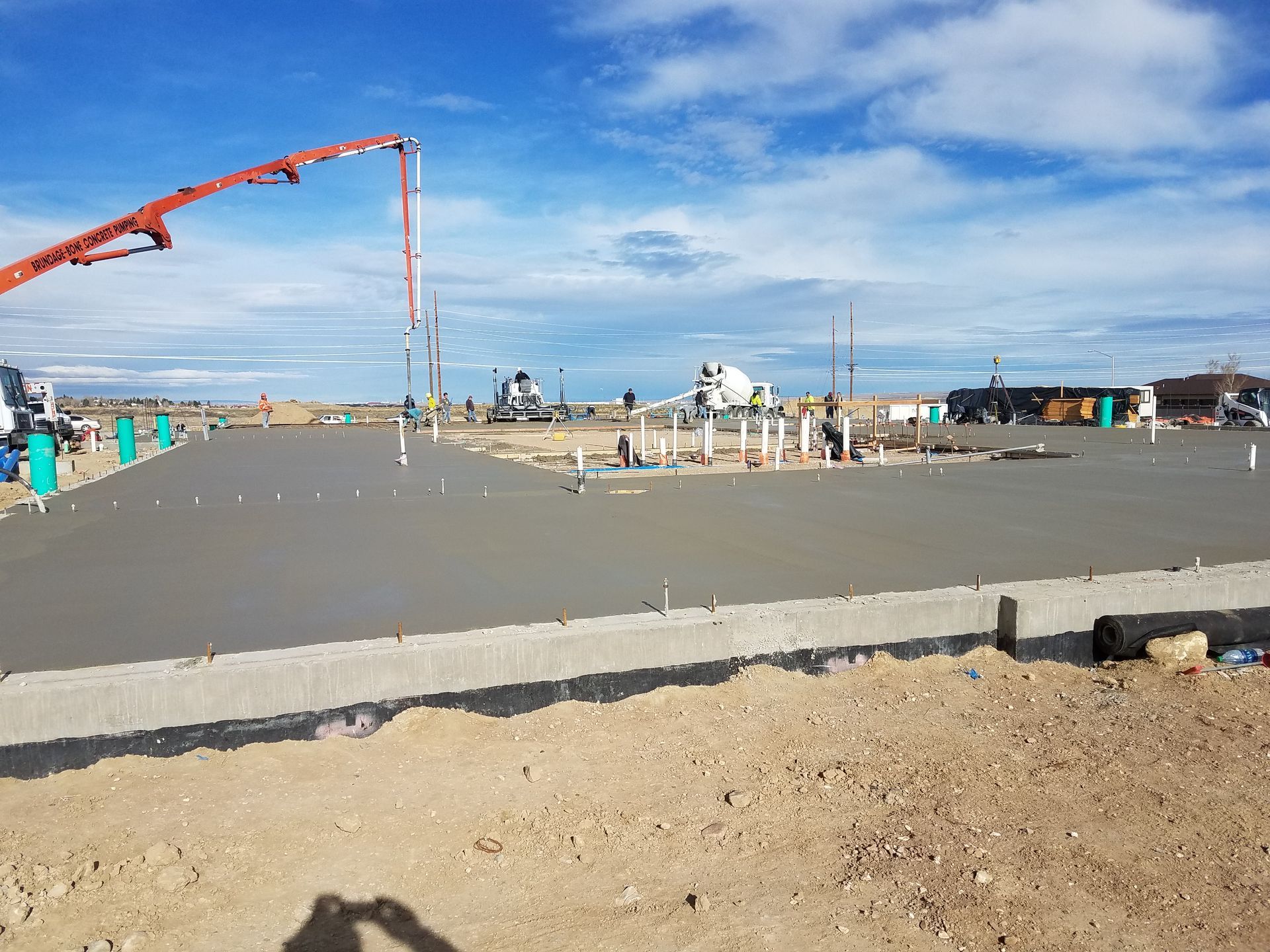 Concrete slab construction site with a red pump boom under a blue sky