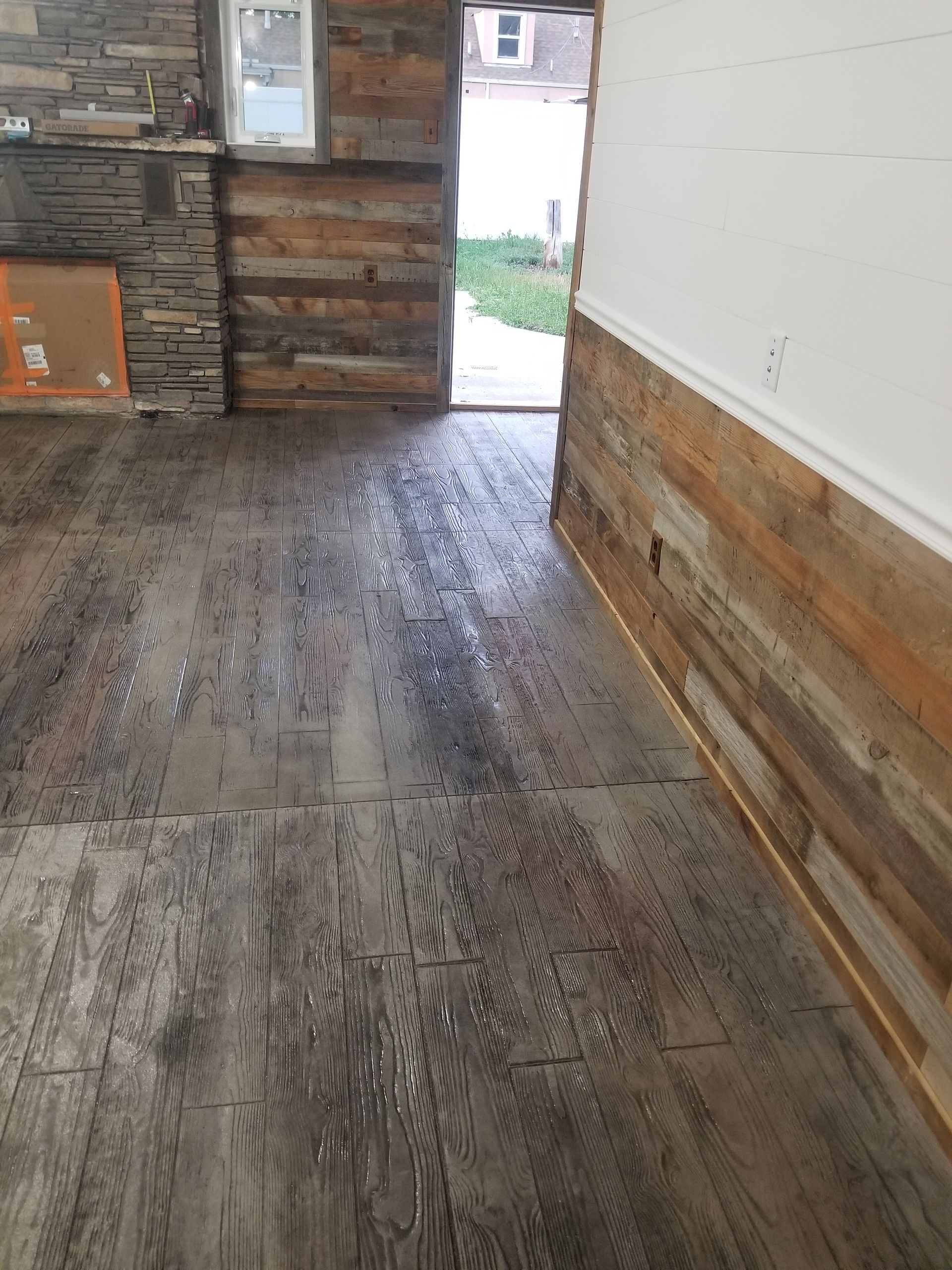 Rustic room with worn wooden floor, log walls, and an open doorway to outside light.