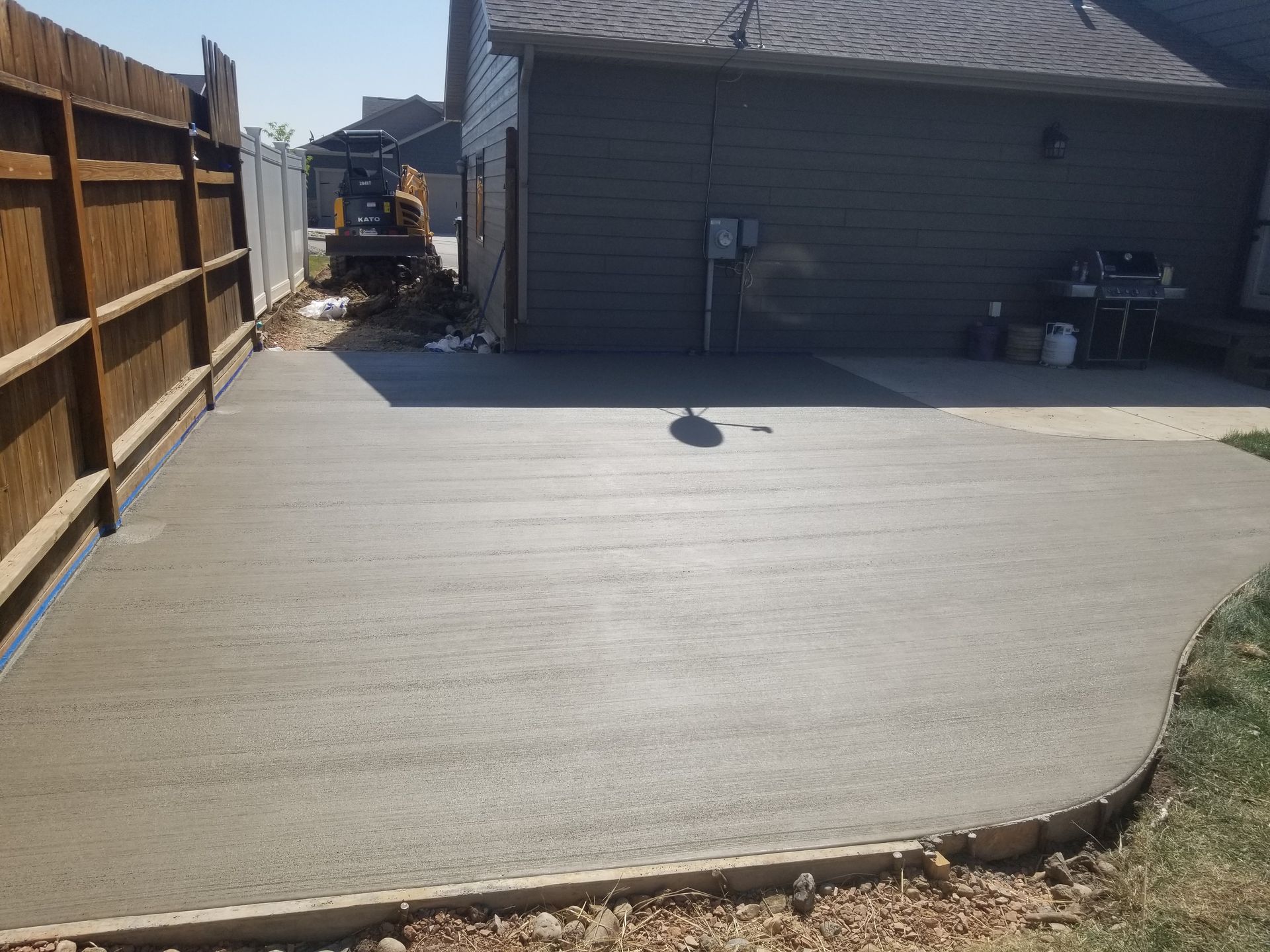 A concrete walkway leading to a house with a brick wall.