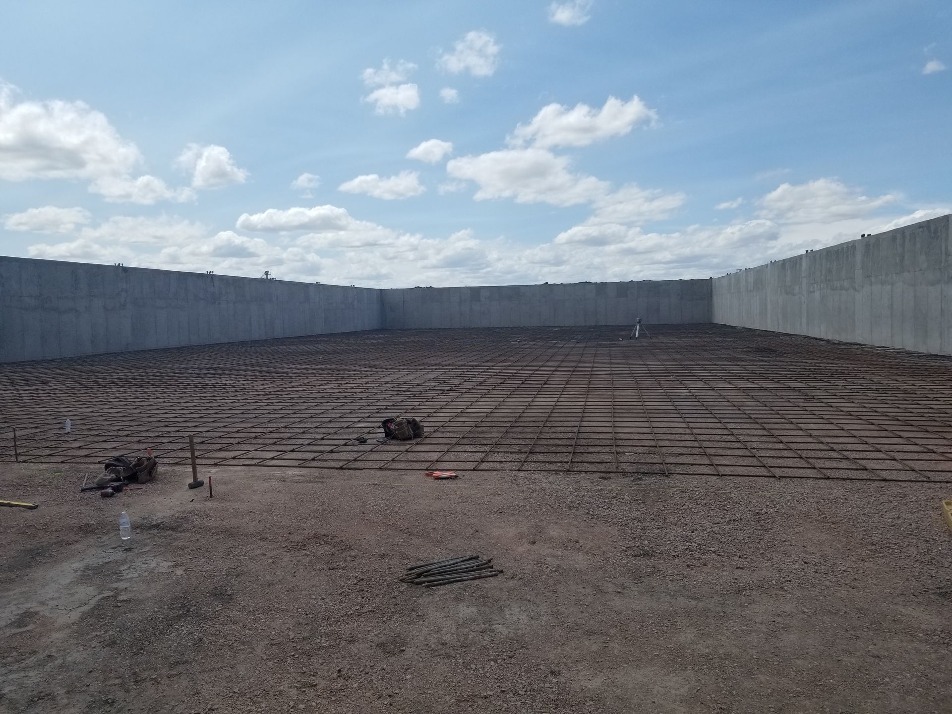 Empty walled construction site under a blue sky with scattered clouds