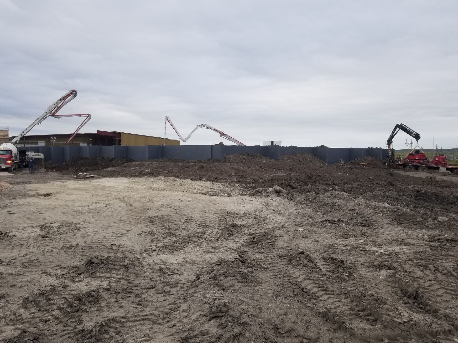 Construction site with excavators and dirt piles under a cloudy sky