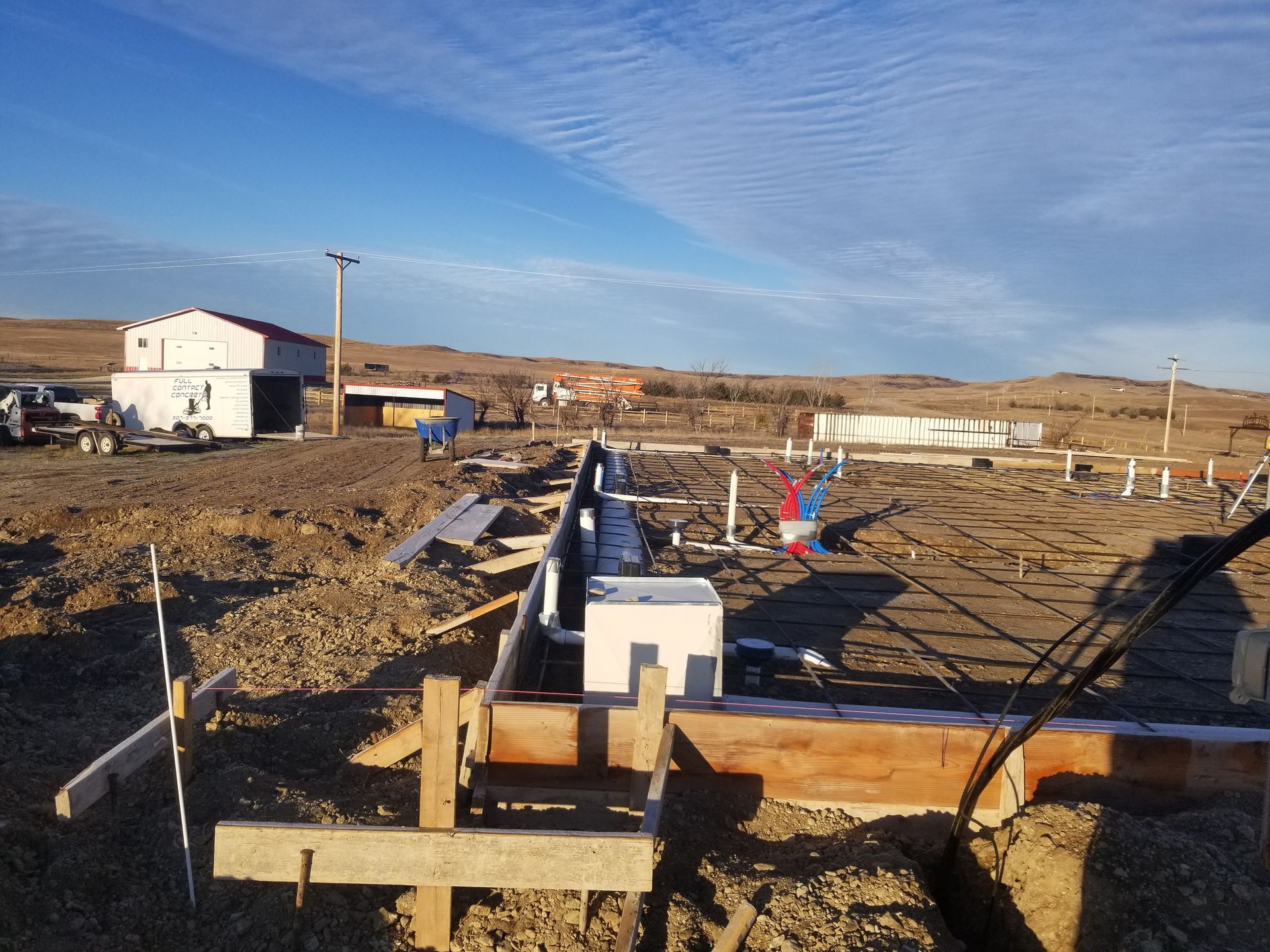 Outdoor construction site with wooden forms and scattered materials under a blue sky