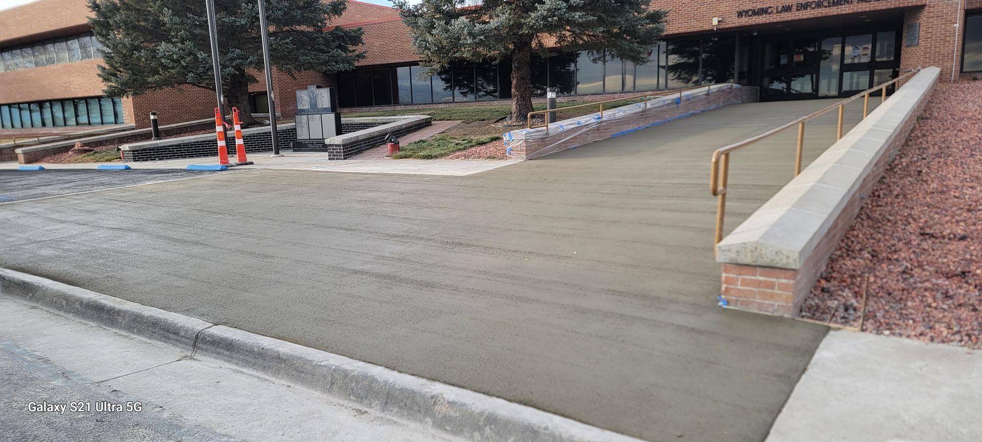 Concrete wheelchair ramp with handrails leading to a building entrance, under construction and cordoned off
