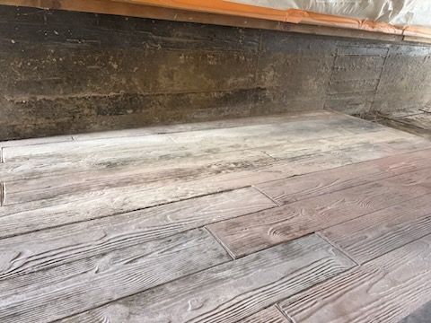 Weathered gray wood floorboards in a rustic room with dark wood walls.