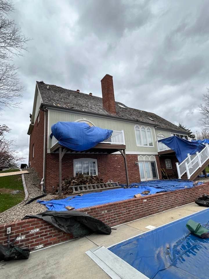 Partially demolished house with blue tarps covering debris and exposed brick walls