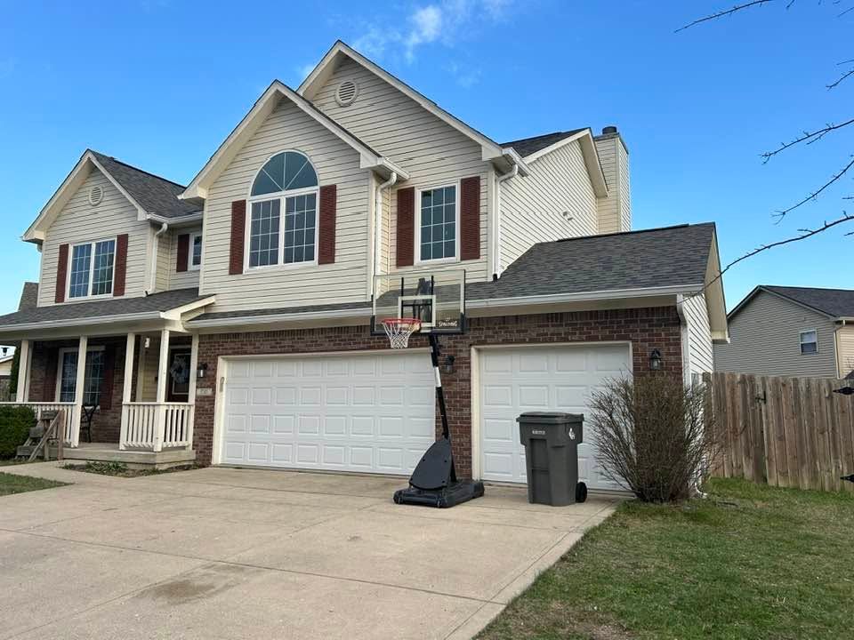 Suburban two-story house with white garage, brick accents, and a driveway