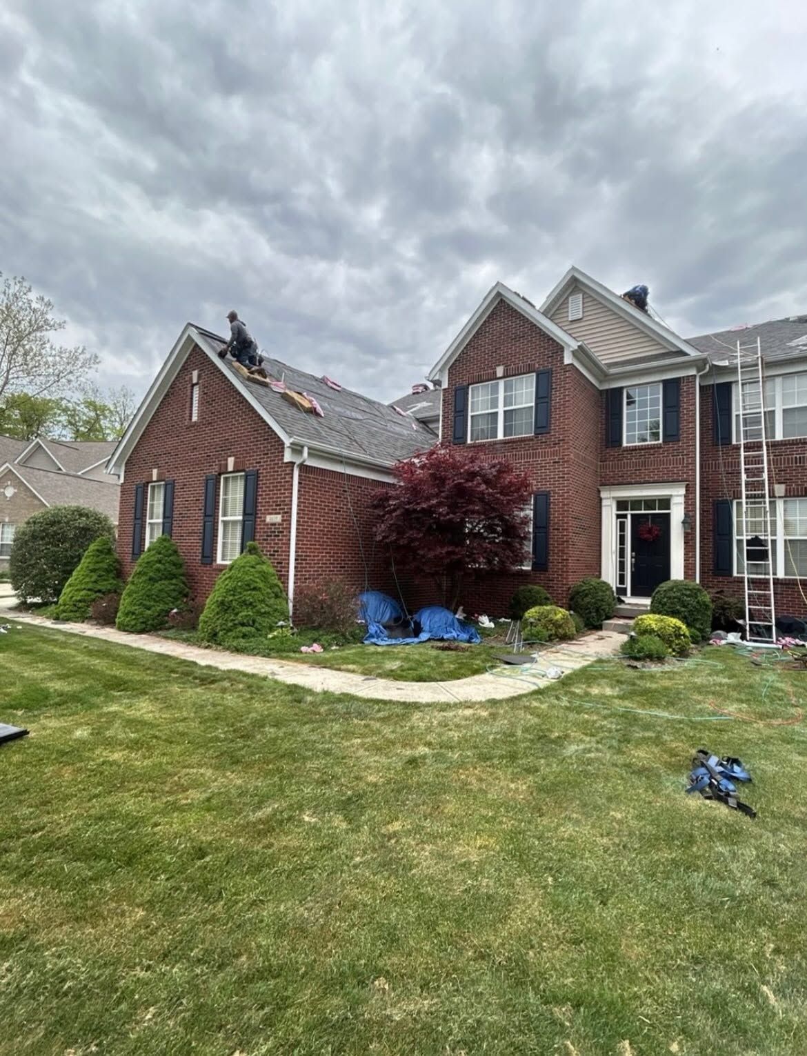 Brick suburban house with white trim, curved walkway, and cloudy sky over a green lawn