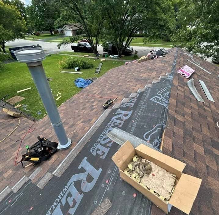 Roof under repair with shingles and tools on a house in a suburban yard