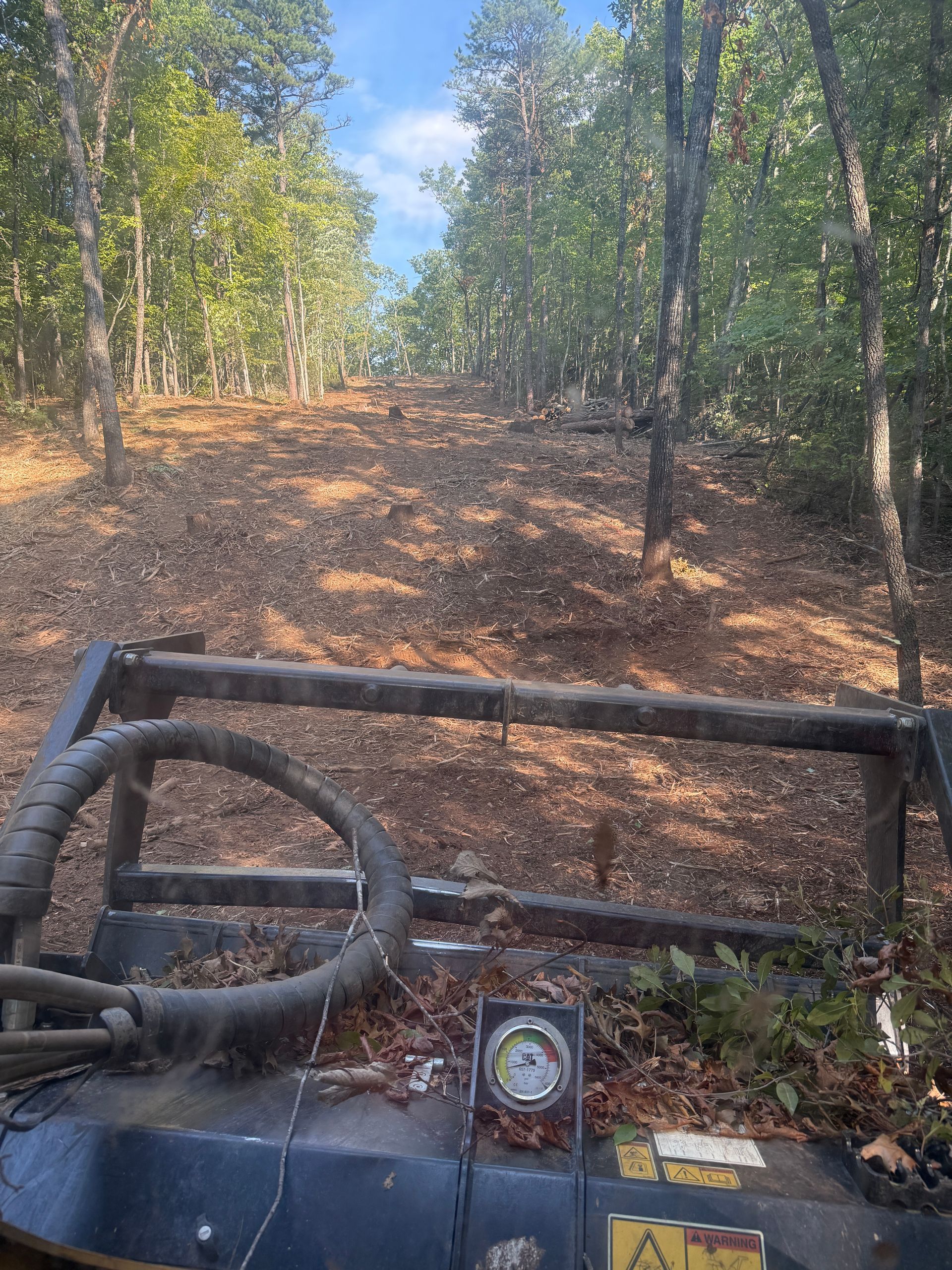 ATV view of a muddy forest trail with trees and a winch in the foreground