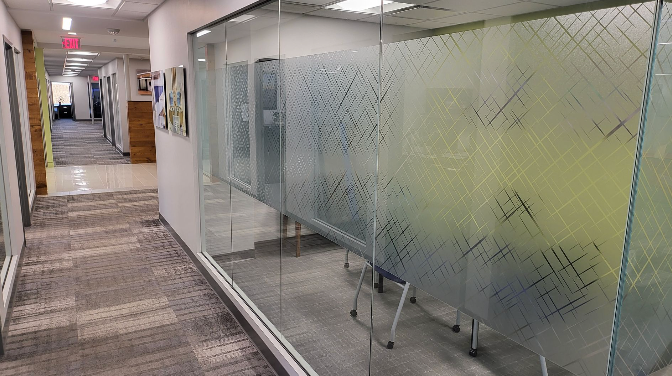 A hallway in an office building with a glass wall.