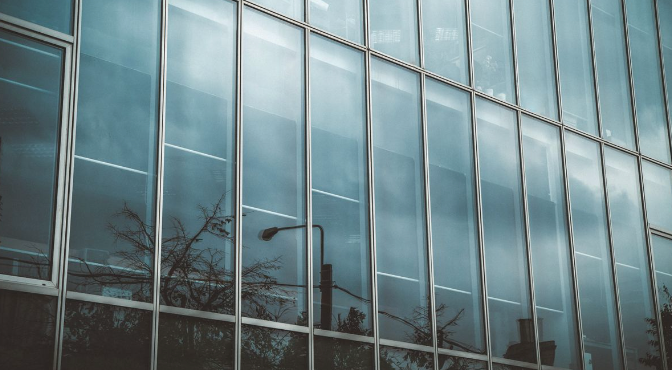 A building with a lot of windows and a reflection of trees in the windows.