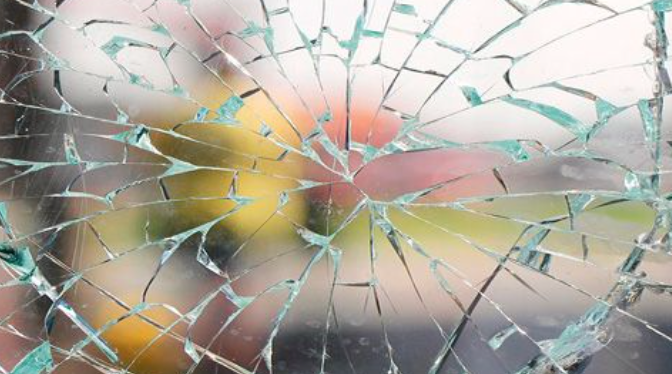 A close up of a broken glass window with a blurry background.