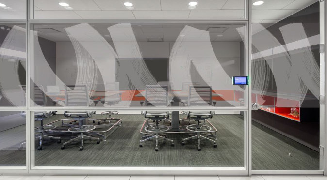 A conference room with a table and chairs behind a glass wall.