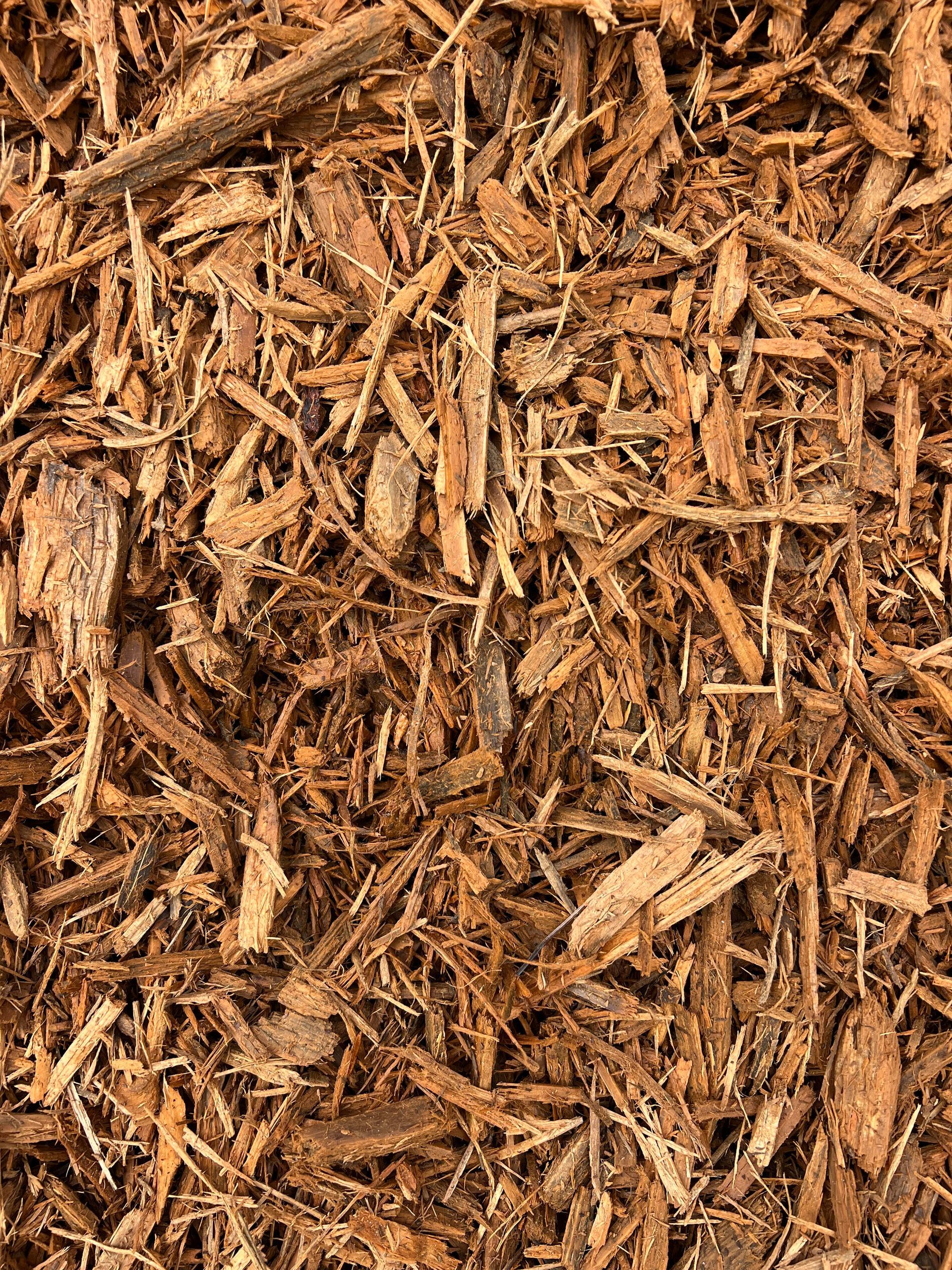 A pile of brown mulch is sitting on the ground.