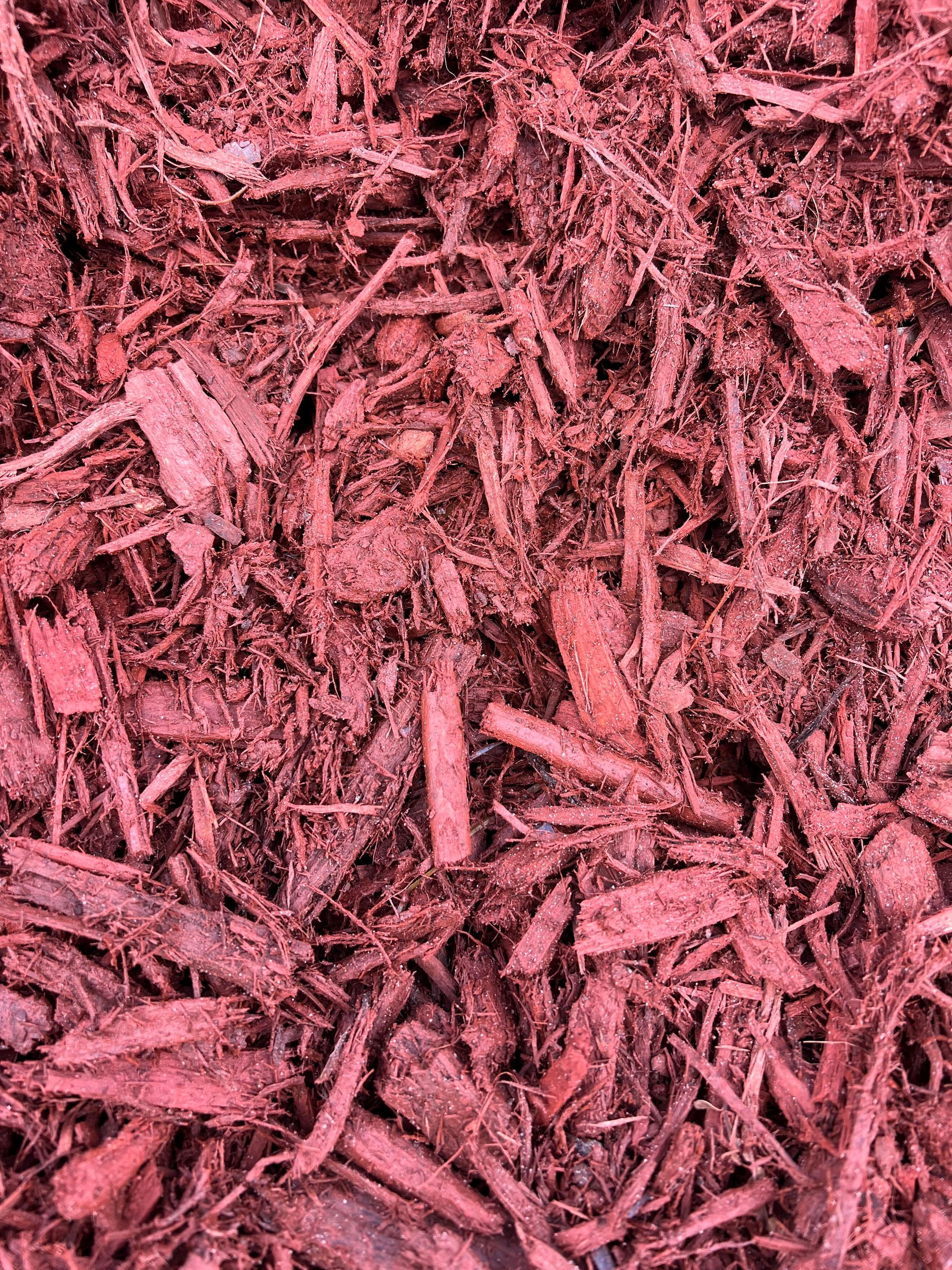 A pile of red mulch is sitting on the ground.