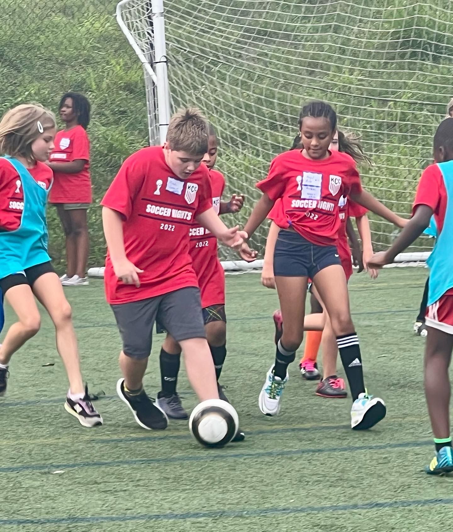 Children in red jerseys playing soccer on an outdoor field