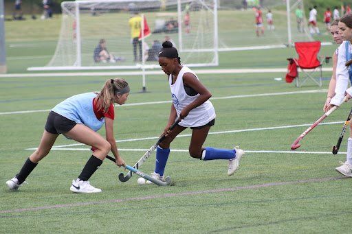 Field hockey players contesting the ball on a turf field during a game
