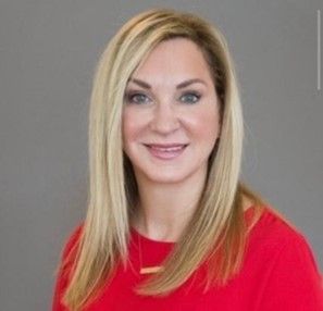 Portrait of a smiling blonde woman in a red top against a gray background
