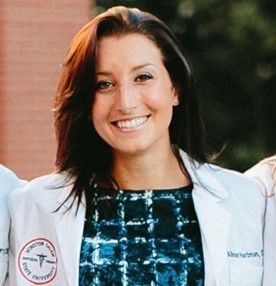 Smiling medical professional in a white lab coat standing outdoors
