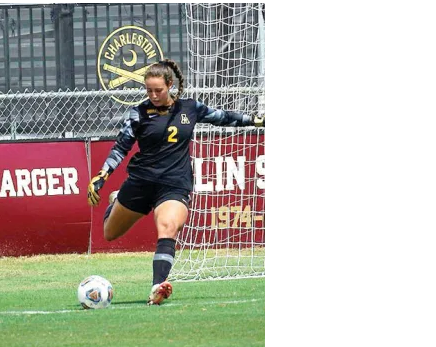 Soccer player in black jersey kicks ball near goal during a match