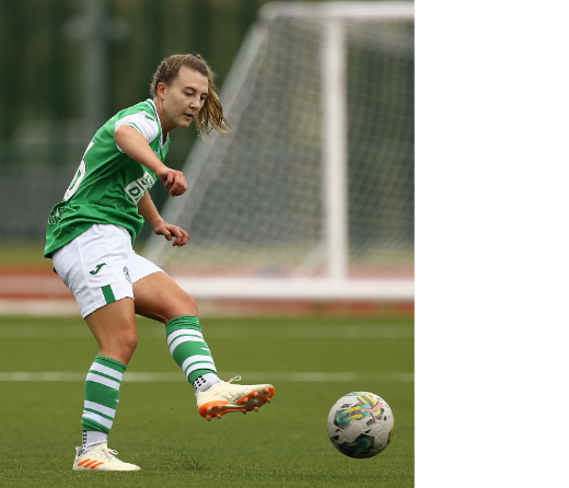 Soccer player in green uniform kicking a ball on the field