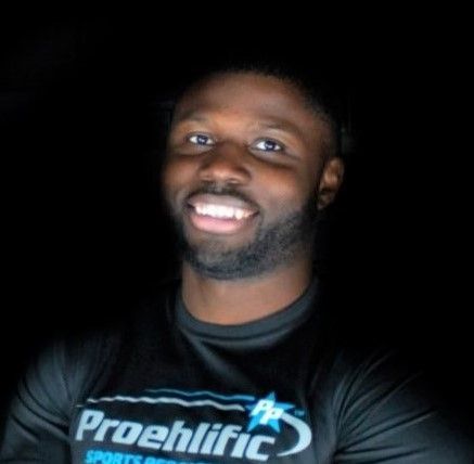 Smiling person in a black Prolific shirt against a dark background