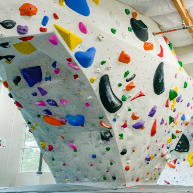 Indoor bouldering wall with colorful holds and overhangs in a bright climbing gym